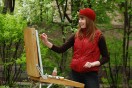 a female plein air artist painting with oils on a portable easel