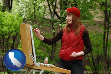 a female plein air artist painting with oils on a portable easel - with California icon