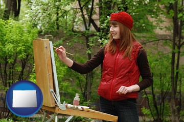 a female plein air artist painting with oils on a portable easel - with Colorado icon