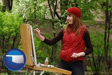 a female plein air artist painting with oils on a portable easel - with Oklahoma icon