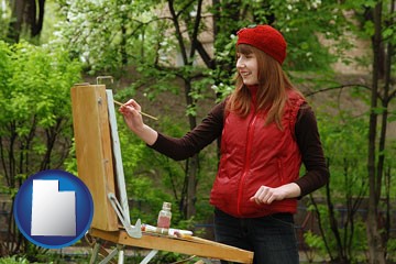 a female plein air artist painting with oils on a portable easel - with Utah icon